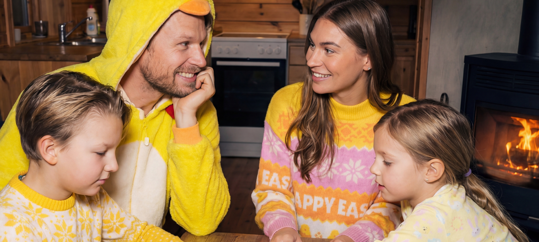 Gezin met twee kinderen in gele paaskleding bij een houtkachel viert samen vrolijk Pasen